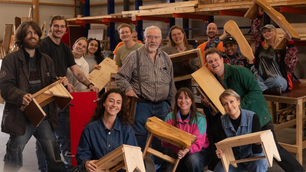 Jongeren en een senior in een werkplaats met houten krukjes